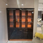 Dark Wood Wine Cabinet with Glass Display Doors, Warm Orange Interior and Stainless Steel Accents